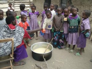Feeding the children porridge before they go home. Previously, they only had boiled roots and leaves to eat once a day. This porridge is much more nutritious and ensures they get more than one meal a day.
